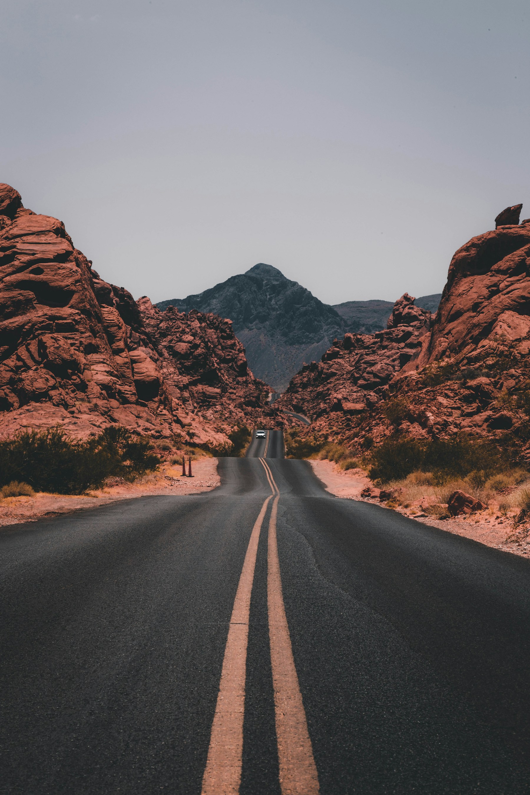 An open two-lane road cuts through red rock country